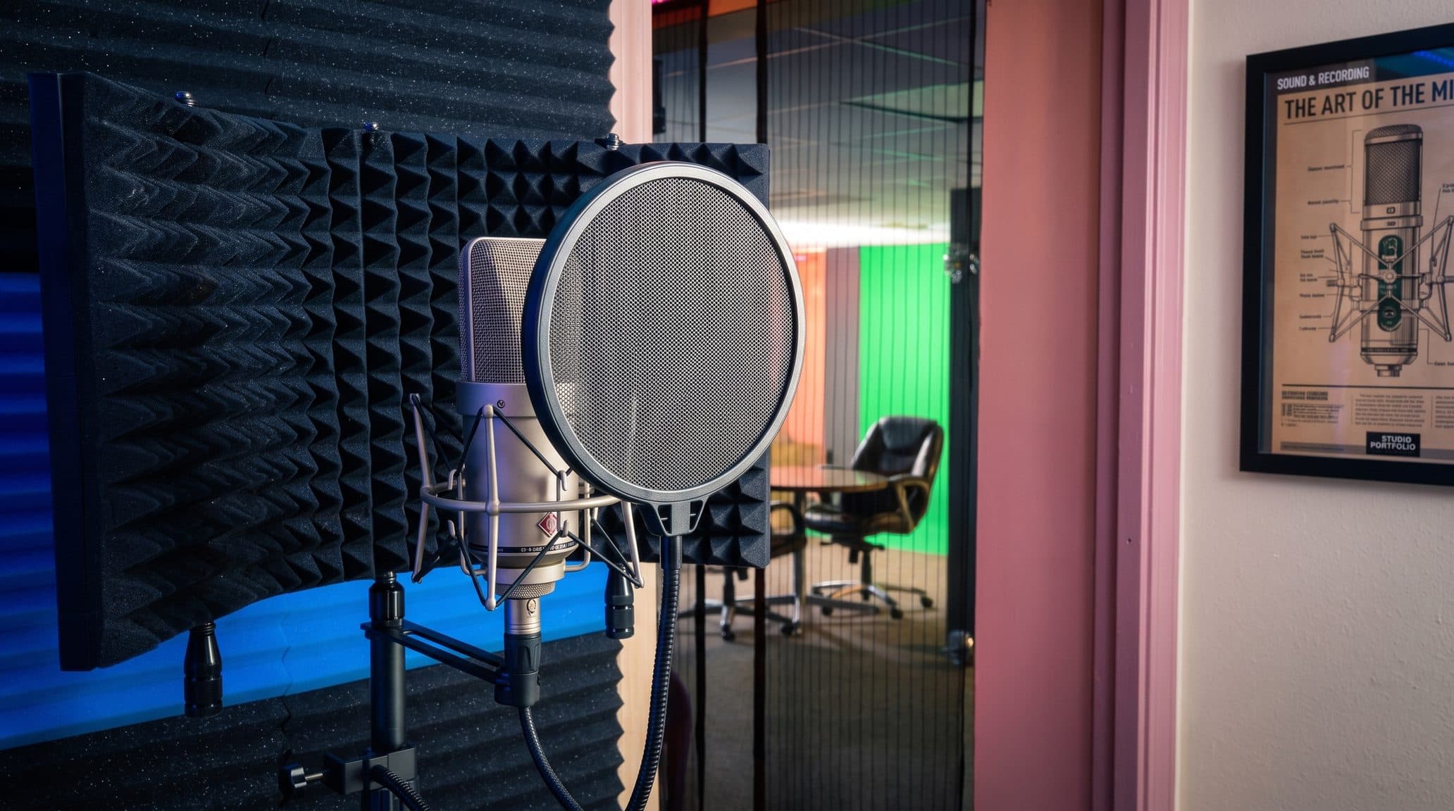A condenser microphone on a stand with a pop filter, set inside an acoustic isolation shield lined with foam